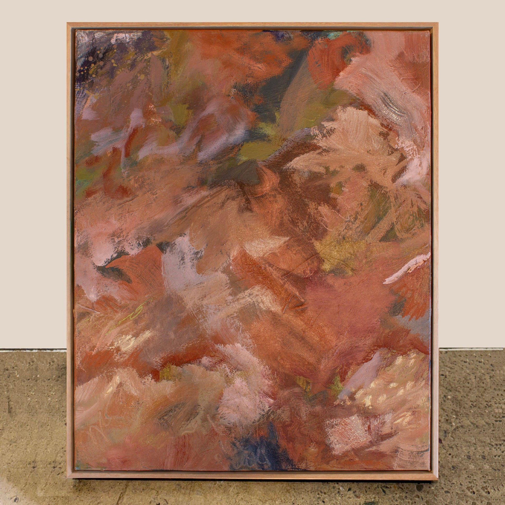Abstract painting with warm colors in a wooden frame on a textured surface.