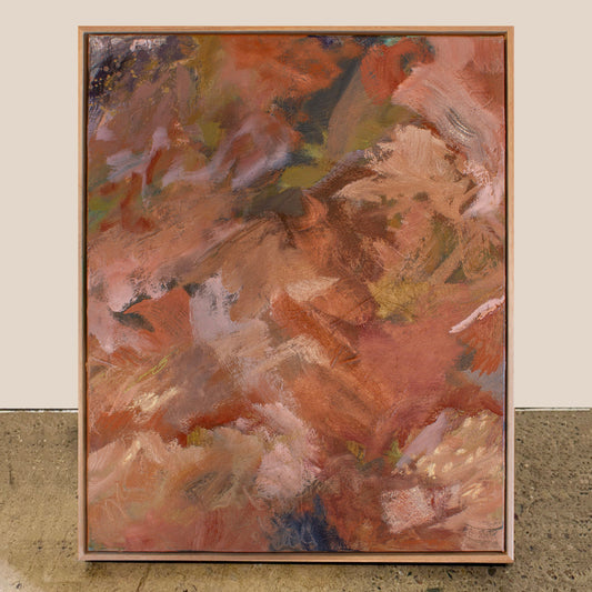 Abstract painting with warm colors in a wooden frame on a textured surface.